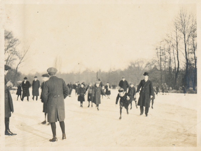 879313 Afbeelding van schaatsende en wandelende mensen op een ijsbaan, vermoedelijk in het Wilhelminapark te Utrecht.